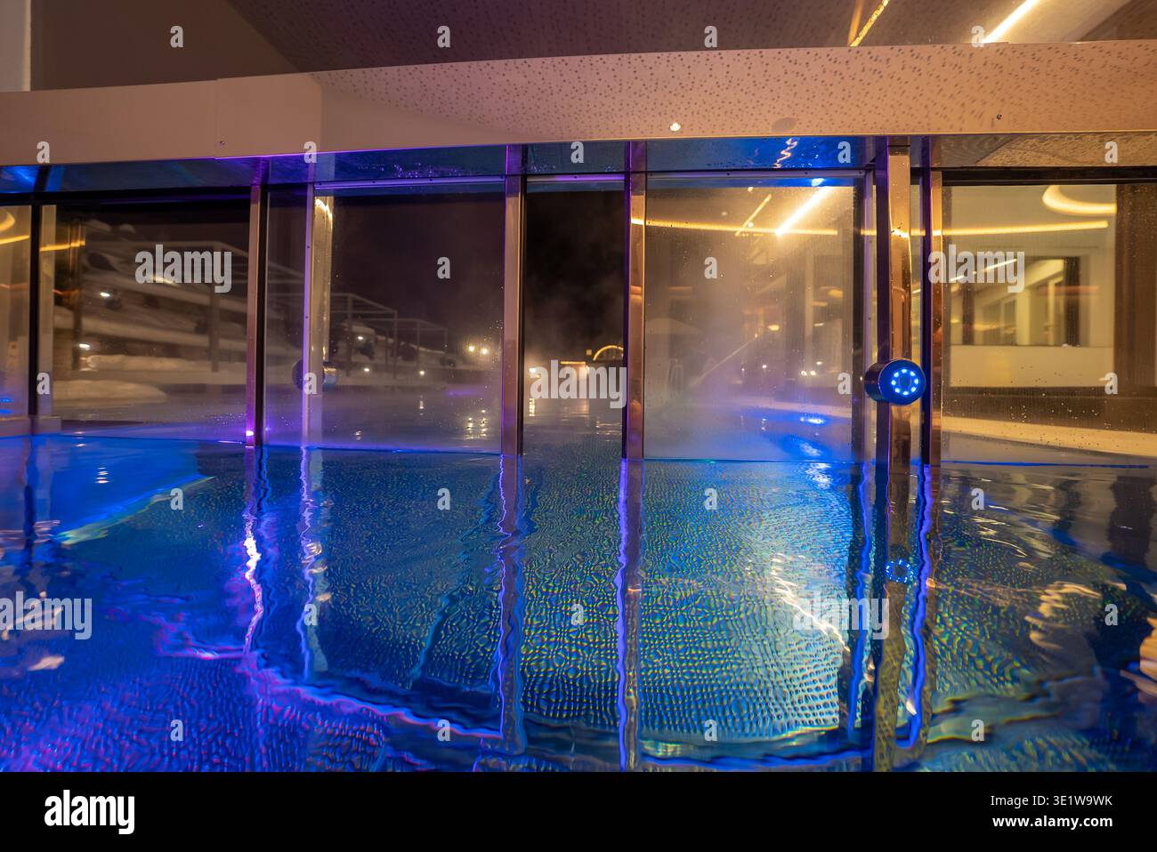 Hallenbad mit Whirlpool im Freien, Mosaikfliesen und LED-Beleuchtung bei Nacht Stockfoto
