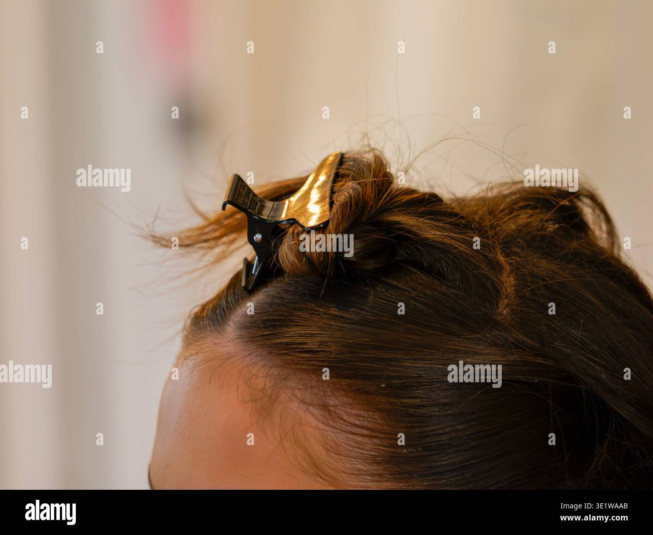 Nahaufnahme eines Frauenhaares, das während der Stylingvorbereitung im Salon mit einem Clip geschnitten wurde. Die Szene beleuchtet den Friseurprozess und die Schönheitspflege, ideal für die Anwendung Stockfoto