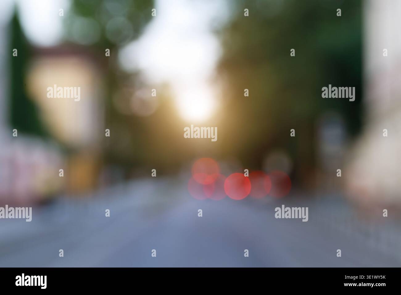 Abstrakter Blick auf eine Straße mit verschwommenen roten Rücklichtern und einem sanften Sonnenlicht schaffen eine traumhafte Atmosphäre Stockfoto