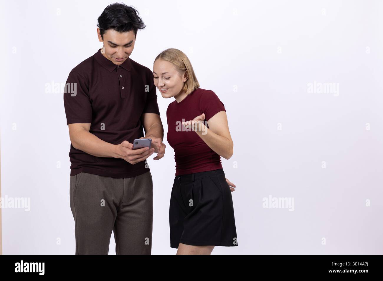 Junge Paare stehen zusammen und schauen auf den Smartphone-Bildschirm Stockfoto