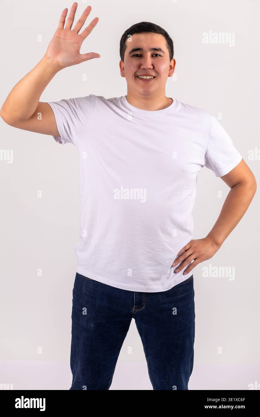 Junger Mann in weißem T-Shirt, der hallo winkt und lächelt Stockfoto