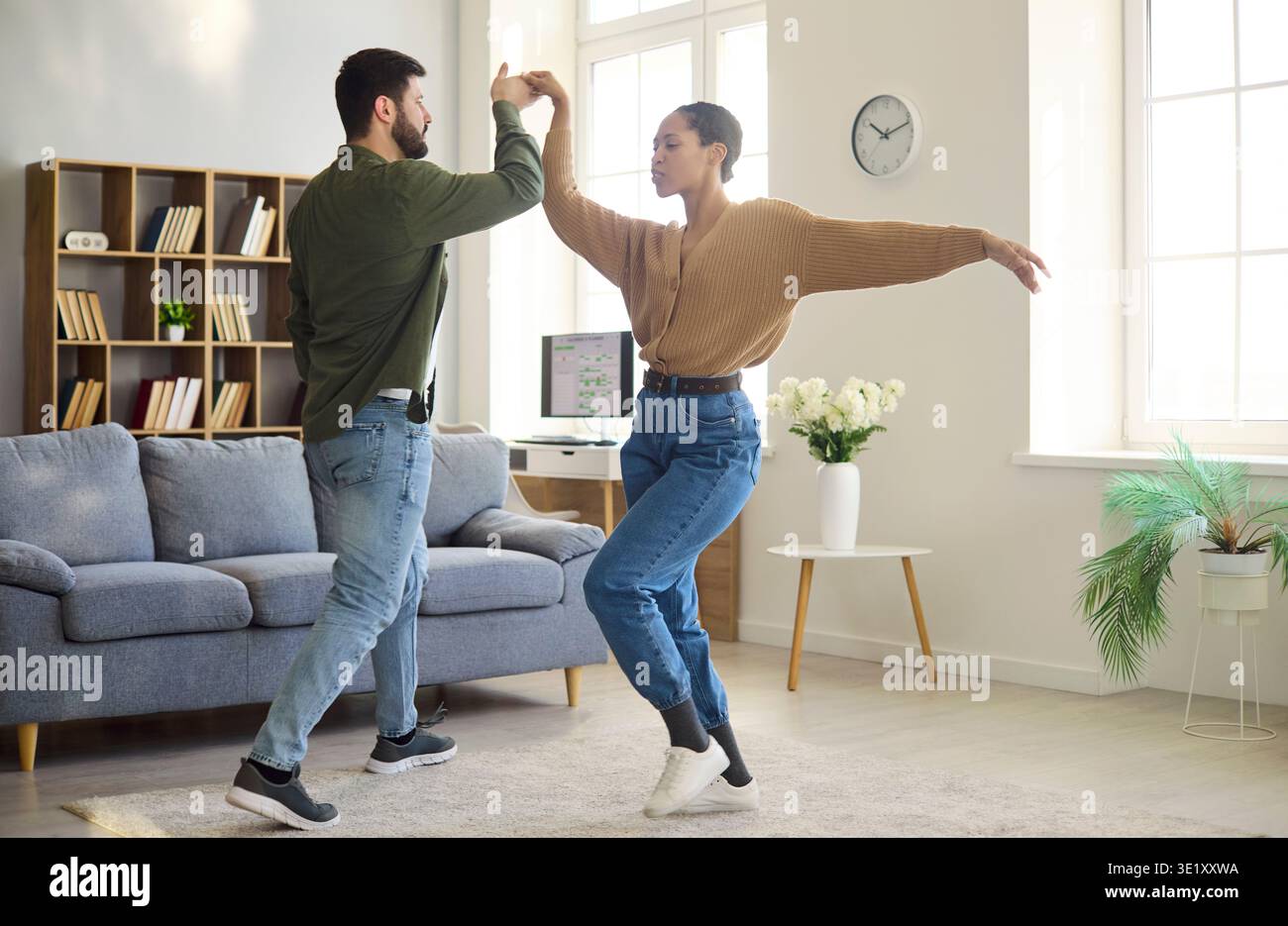 Glückliches Paar, das zu Hause in einem hellen Wohnzimmer zusammen tanzt, Lifestyle-Moment Stockfoto