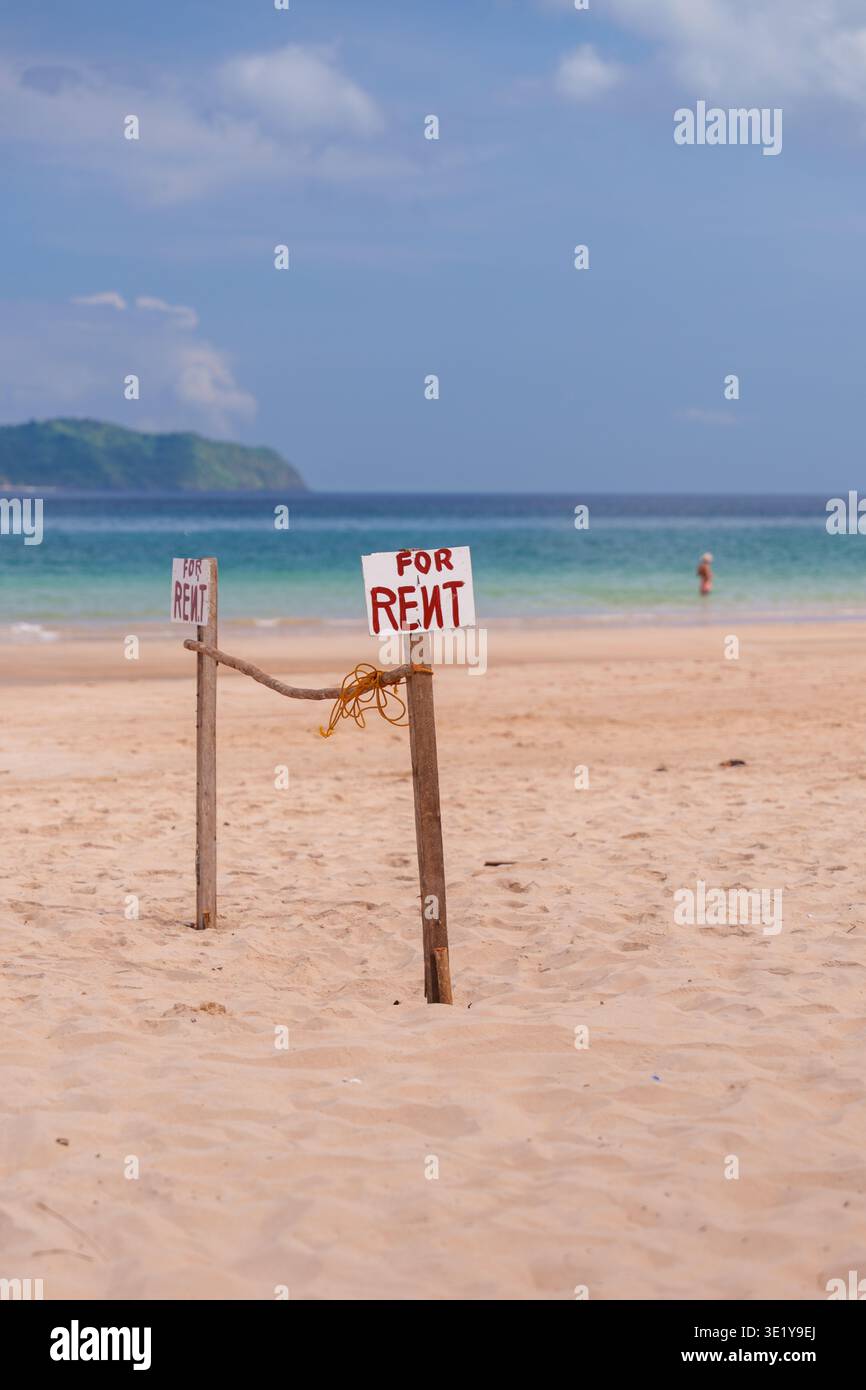 Einfaches hölzernes Schild mit „for rent“-Text am tropischen Sandstrand mit Meer und Küste im Hintergrund in Palawan, Philippinen Stockfoto