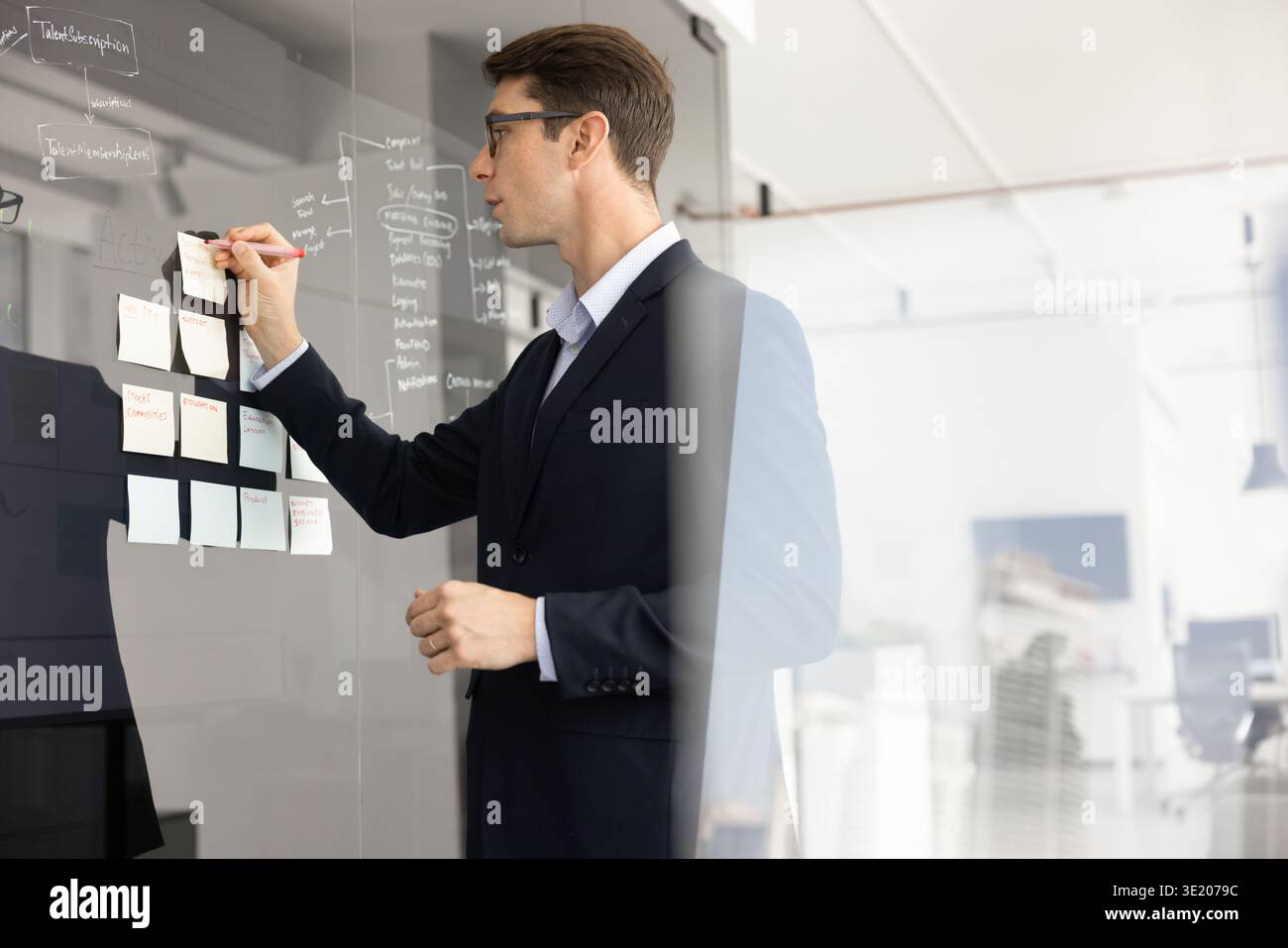 Ein junger Geschäftsmann schreibt neue Ideen oder Updates auf Haftnotizen Stockfoto