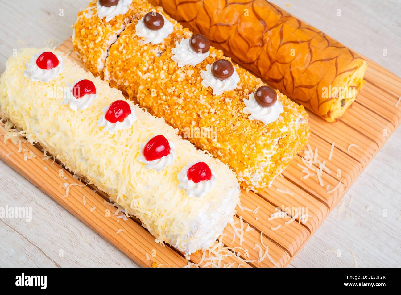 Drei köstliche Schweizer Brötchen mit Creme Frosting und Kirschen auf Holzbrett Stockfoto