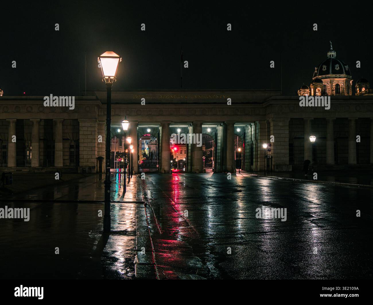 Heldenplatz Wien bei Nacht: Volks-Theater und MuseumsQuartier, beleuchtete Gebäude und nasser Bürgersteig, dramatische Lichter der Stadt. Stockfoto