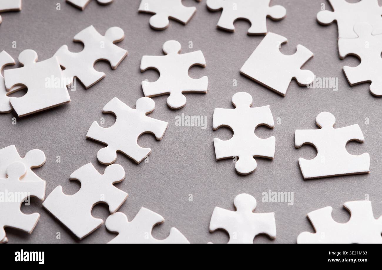 Sammlung leerer Puzzleteile auf einer grauen Oberfläche, angeordnet in einem zufälligen Muster Stockfoto