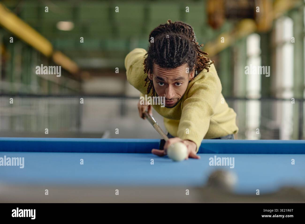 Junger Erwachsener Schwarzer Mann, der Billard spielt und Cue Ball in der Poolhalle anvisiert Stockfoto