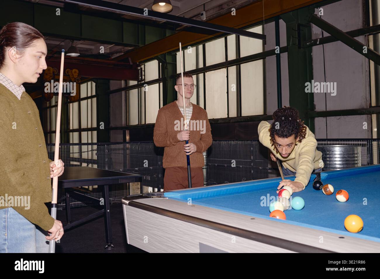 Junge multiethnische Freunde spielen gemeinsam Billard im modernen Freizeitzentrum Stockfoto