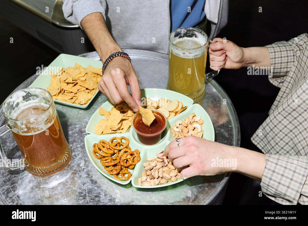 Junge Erwachsene Mann und Frau teilen Bier und Snacks bei einem Social Meeting Stockfoto