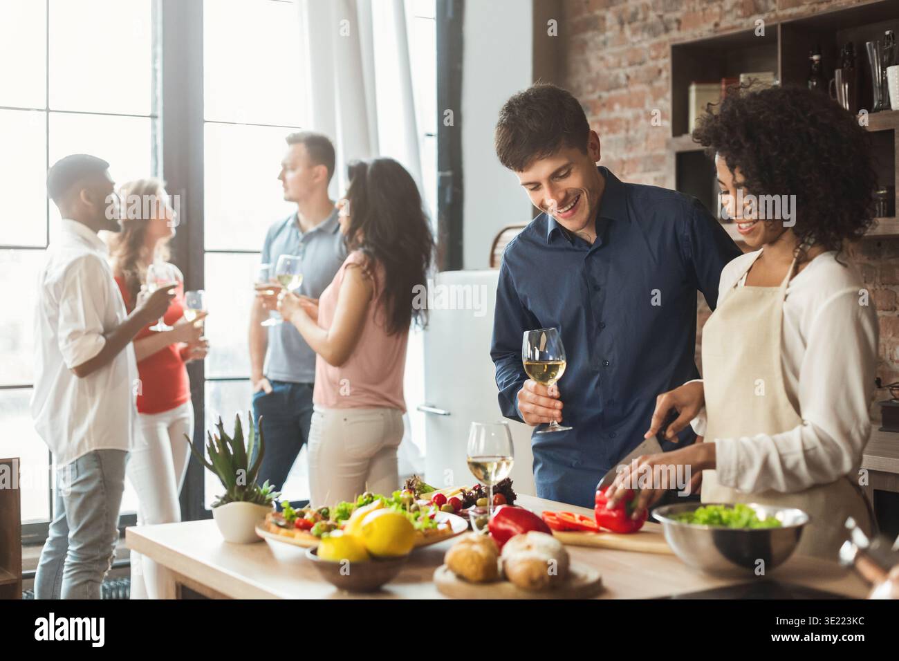 Ein multiethnisches Paar bereitet mit Freunden ein Abendessen in der Küche vor Stockfoto