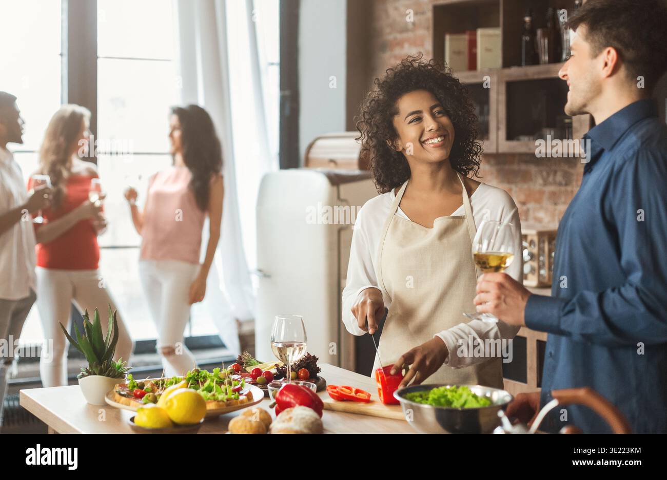 Süßes, junges gemischtes Paar, das in der Küche Abendessen zubereitet Stockfoto