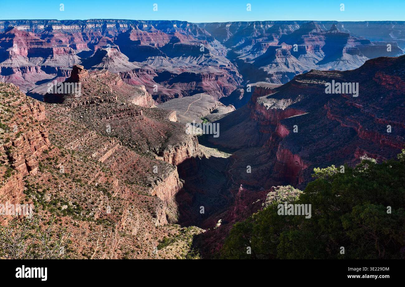 Weitläufiger Blick auf den Grand Canyon unter einem klaren blauen Himmel mit felsigen Schichten und Klippen. Grand Canyon, Arizona, USA Stockfoto