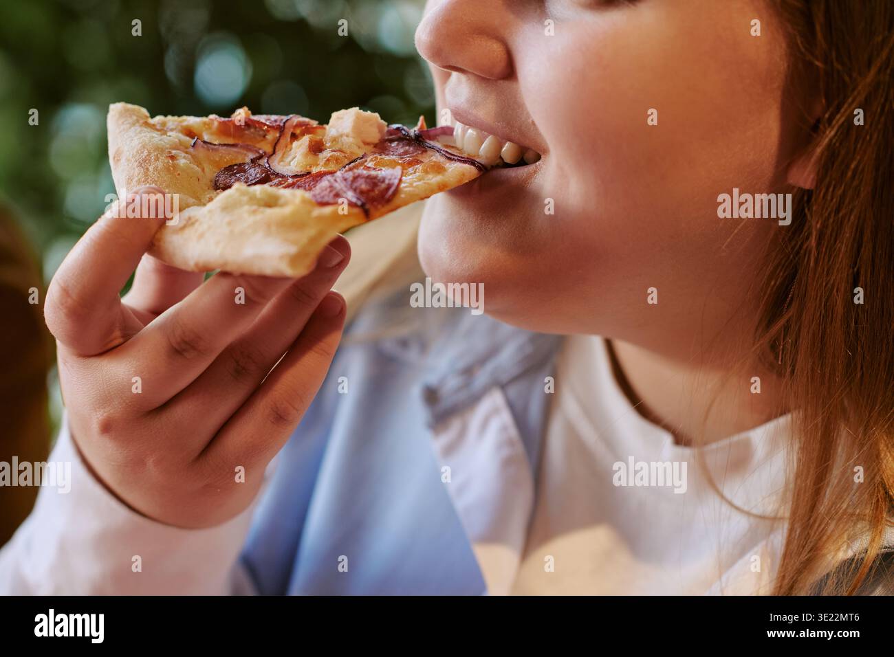 Eine junge Frau genießt Pizza im Freien Stockfoto