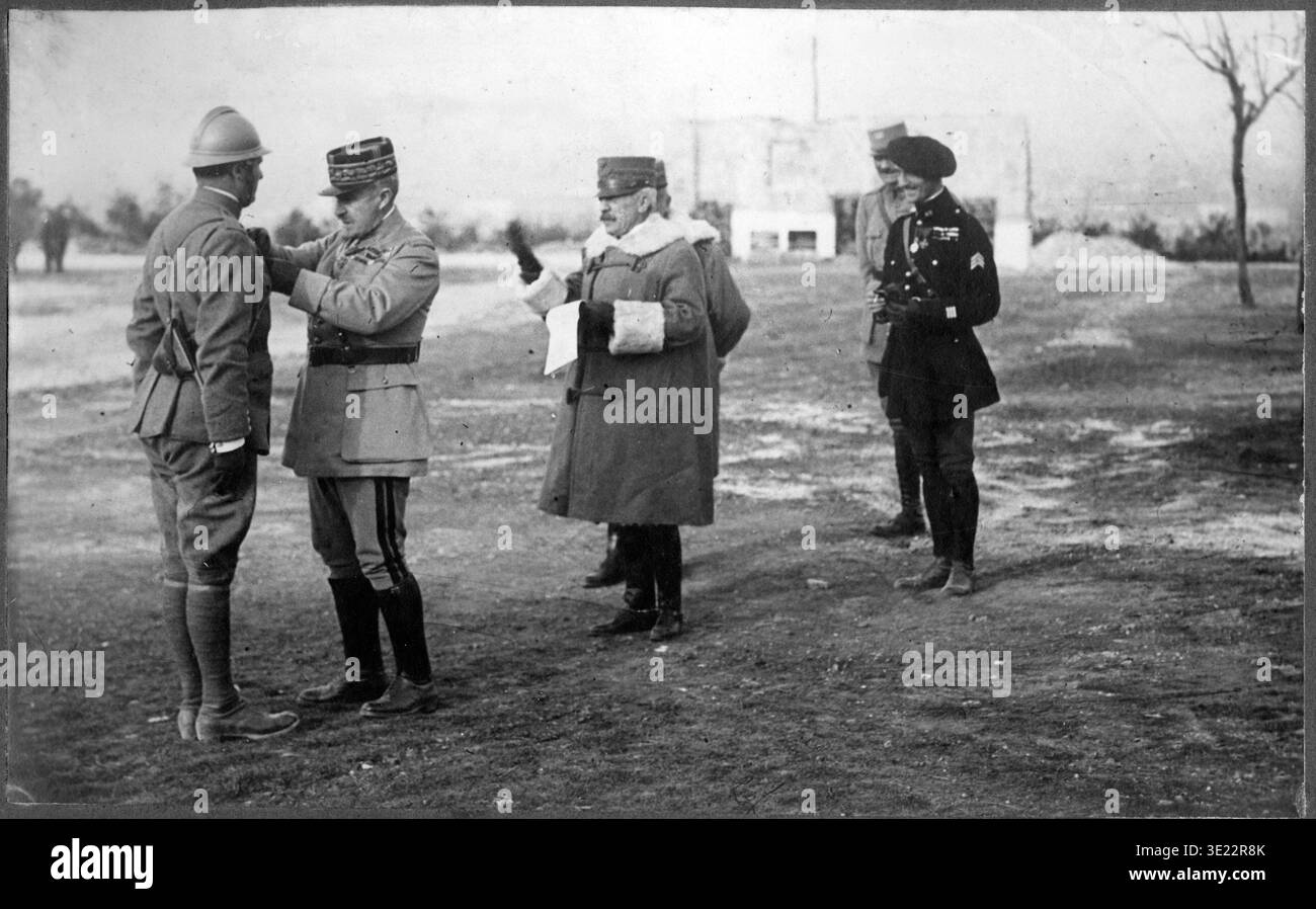 Französischer General Robert Nivelle vergibt Medaille an italienischen Offizier, König Vittorio Emanuele III. Anwesend, Isonzo-Front des Ersten Weltkriegs – Schwarzweiß-Foto aus dem Ersten Weltkrieg, das den französischen General Robert Nivelle (später Oberbefehlshaber) zeigt, der einem italienischen Armeeoffizier während einer Zeremonie an der italienischen Front (Isonzo/Soča-Schlachten) persönlich eine militärische Auszeichnung (wahrscheinlich Croix de Guerre) verleiht. Nivelle in Großmantel und Kepi stiftet die Medaille, während König Vittorio Emanuele III. In der Nähe im Mantel steht. Andere Offiziere in Adria-Helmen und Uniformen sind auf einem offenen Feld anwesend. Stockfoto