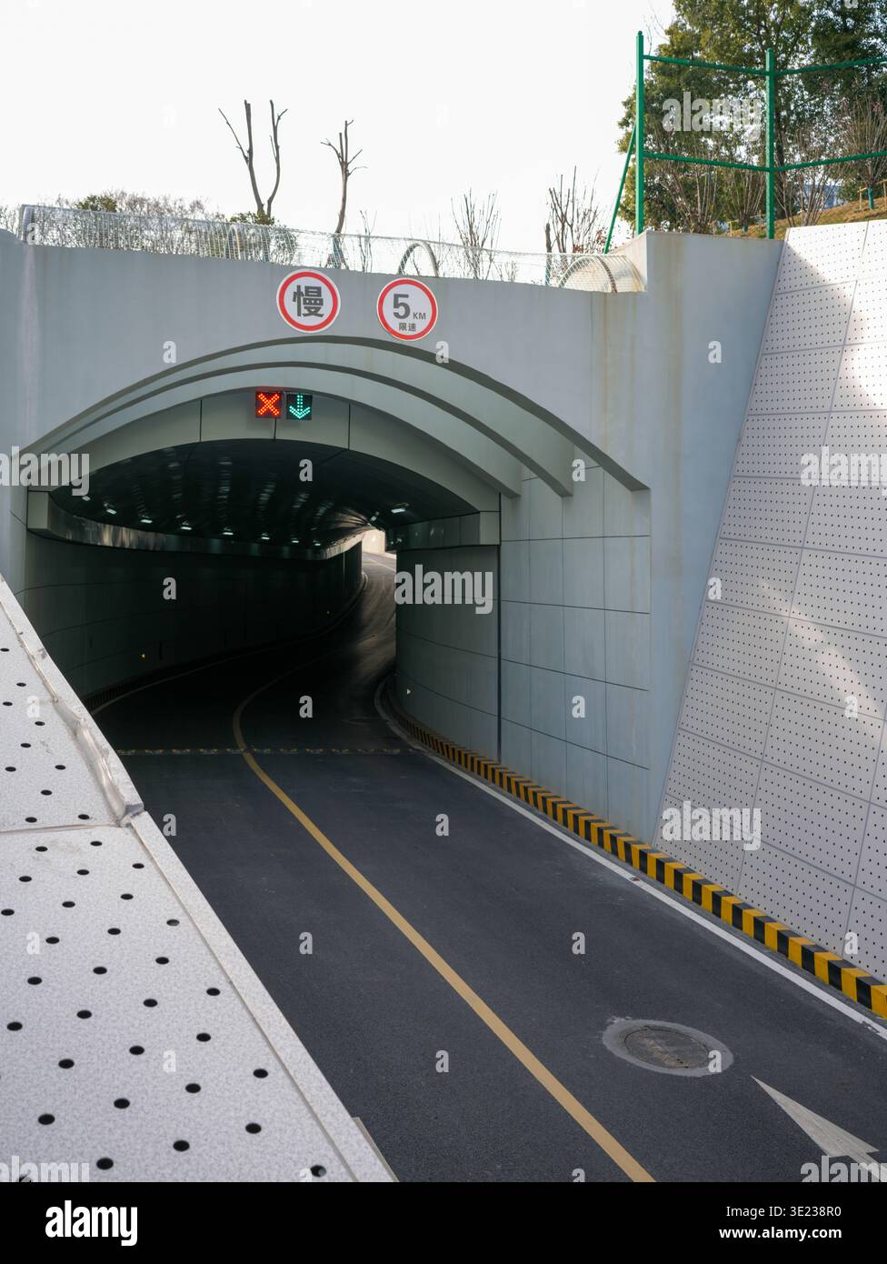 Blick auf eine leere Asphaltstraße, die in einen bogenförmigen städtischen unterirdischen Tunnel führt, der mit roten und grünen Ampelsignalen ausgestattet ist. Die wh Stockfoto