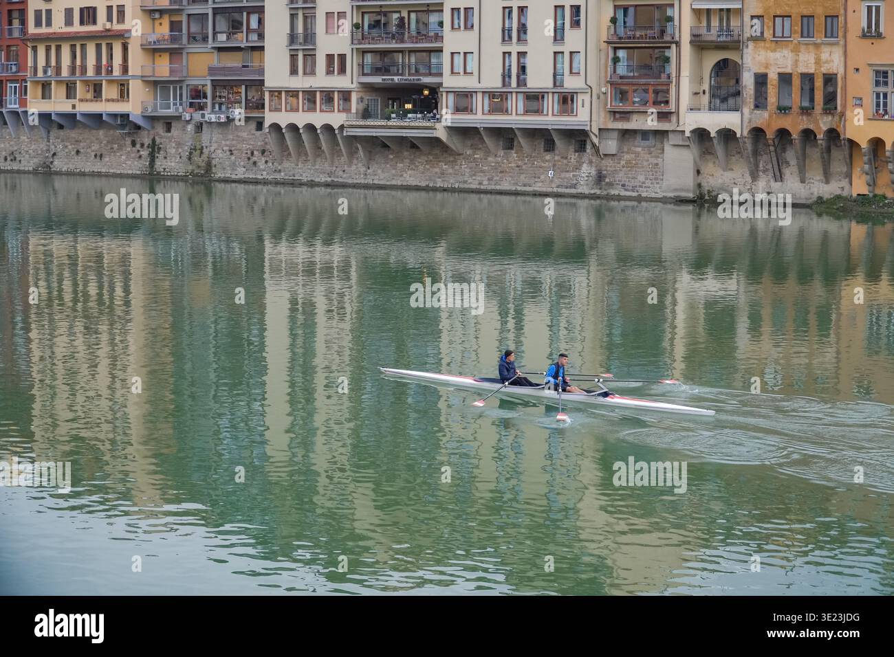 Zwei Personen, die auf dem Fluss Arno mit historischen Gebäuden im grünen Wasser schweben, Florenz, Italien. Stockfoto