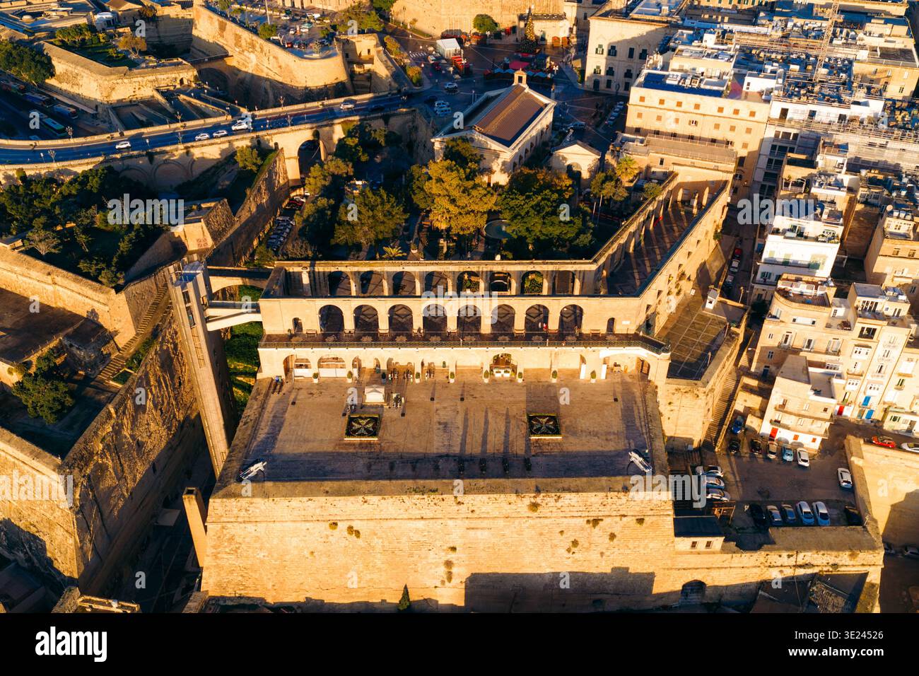 Aus der Vogelperspektive auf die Upper Barrakka Gardens und die Saluting Battery, alte Steinmauern im Kontrast zu den grünen Bäumen und dem blauen Himmel, Valletta, Malta Stockfoto