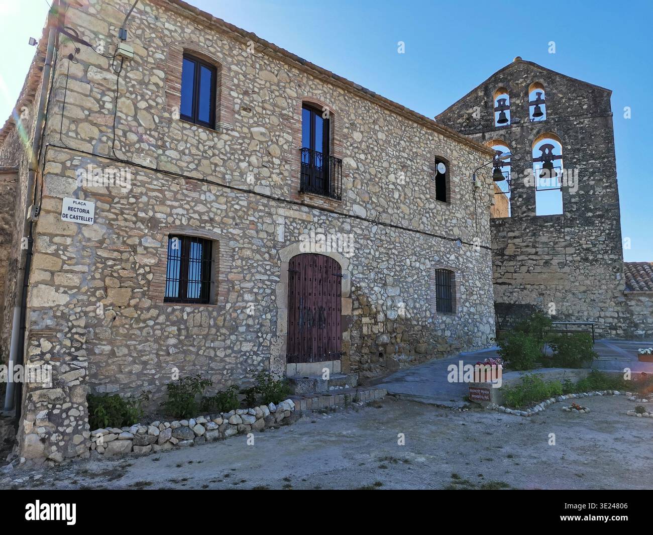 Rustikales Steinhaus und alter Kirchturm im Dorf Castellet, Spanien. Stockfoto