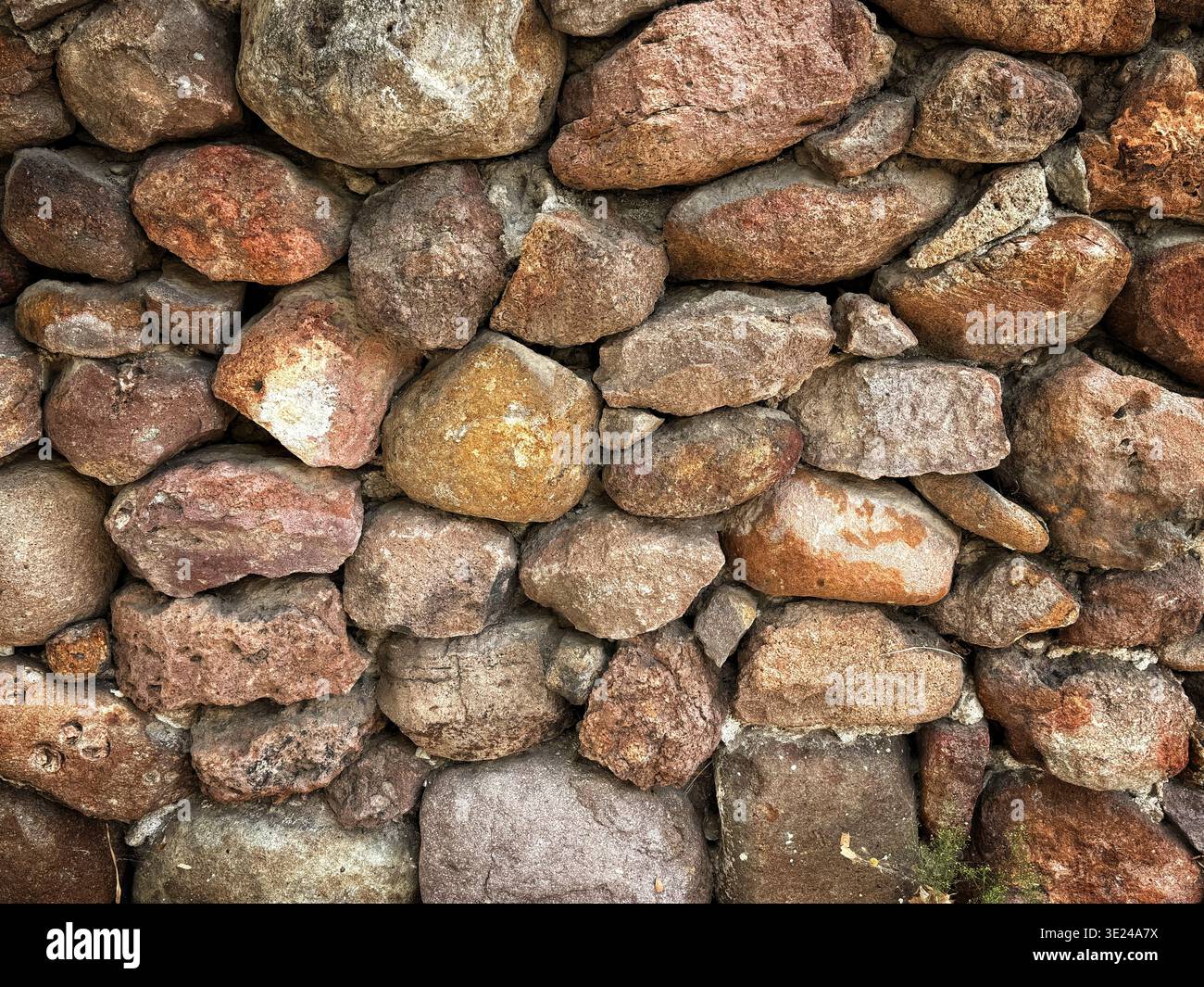 Eine aus nächster Nähe errichtete alte Steinmauer mit unregelmäßig geformten Felsen und Steinen in verschiedenen Farben und Größen Stockfoto