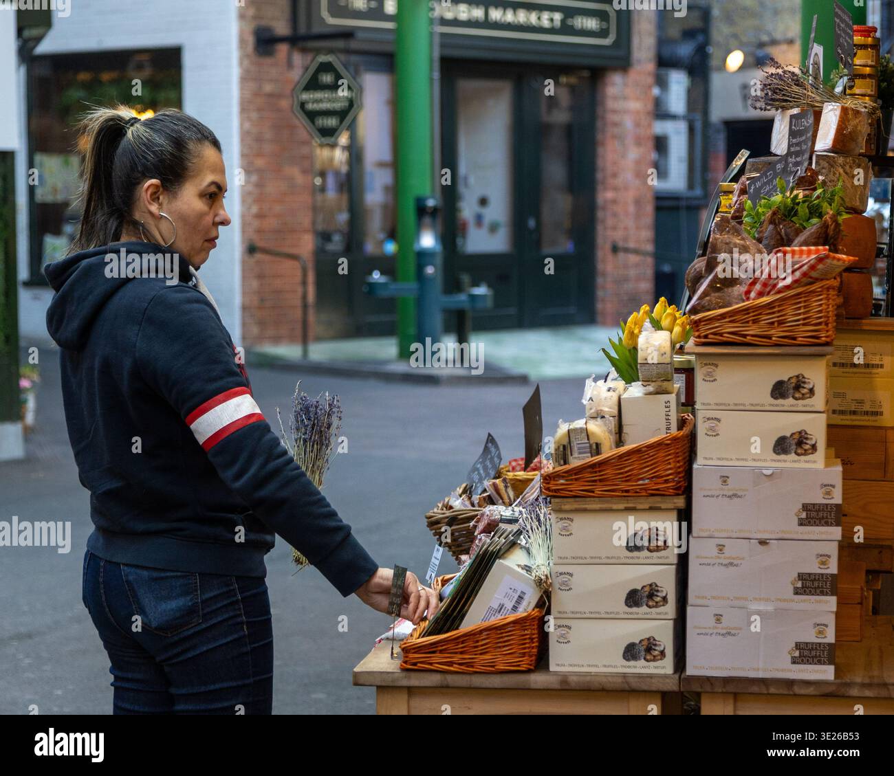 Frau Ladenbesitzerin, die frische Produkte an einem Lebensmittelstand im Freien auf dem Stadtmarkt vorstellt Stockfoto