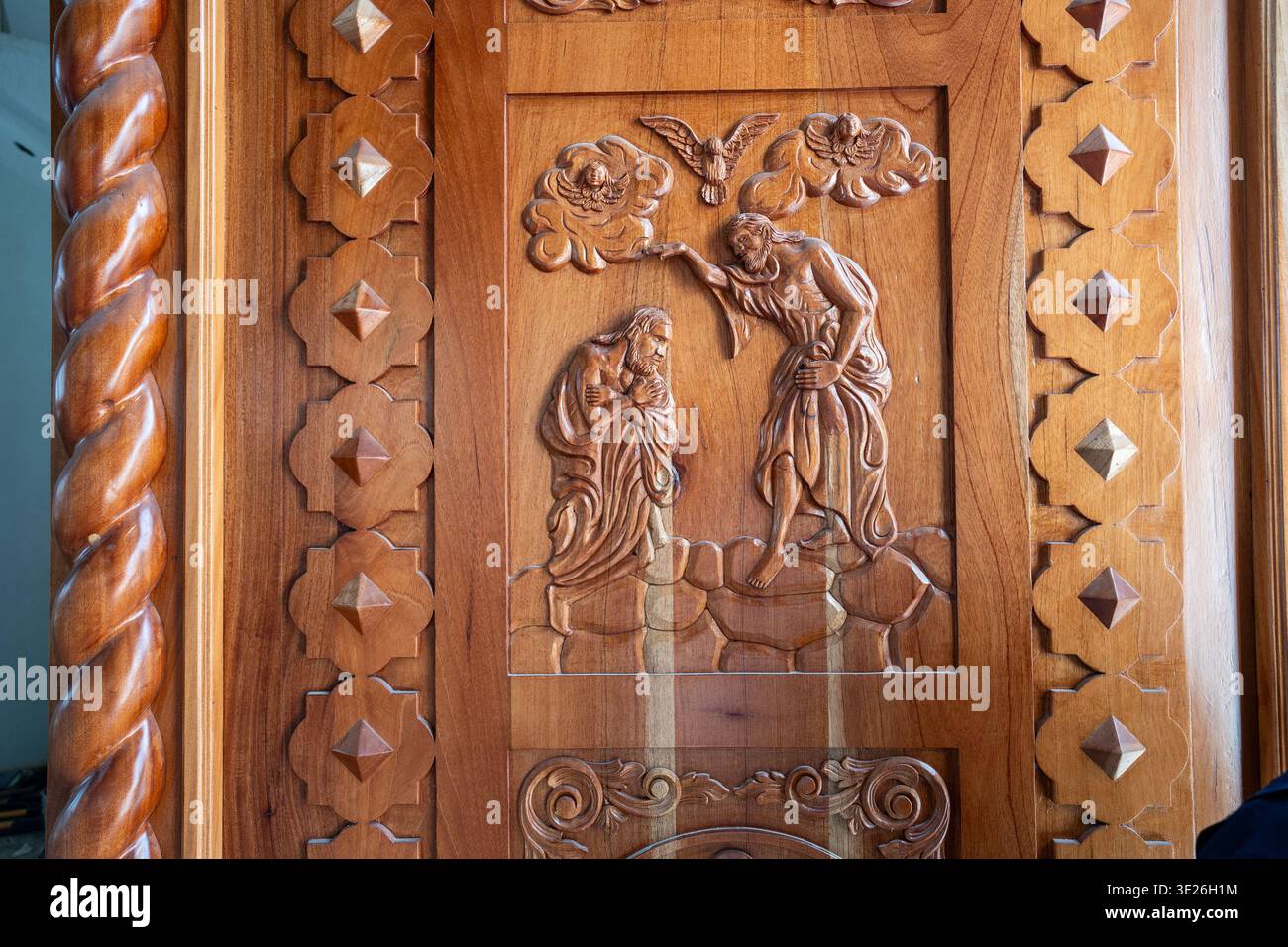 Aguacatan, Guatemala - kompliziertes Holzrelief, das die Taufe Christi mit Johannes dem Täufer zeigt, Taubenmotiv und dekorative geometrische Grenzen. Warm Stockfoto