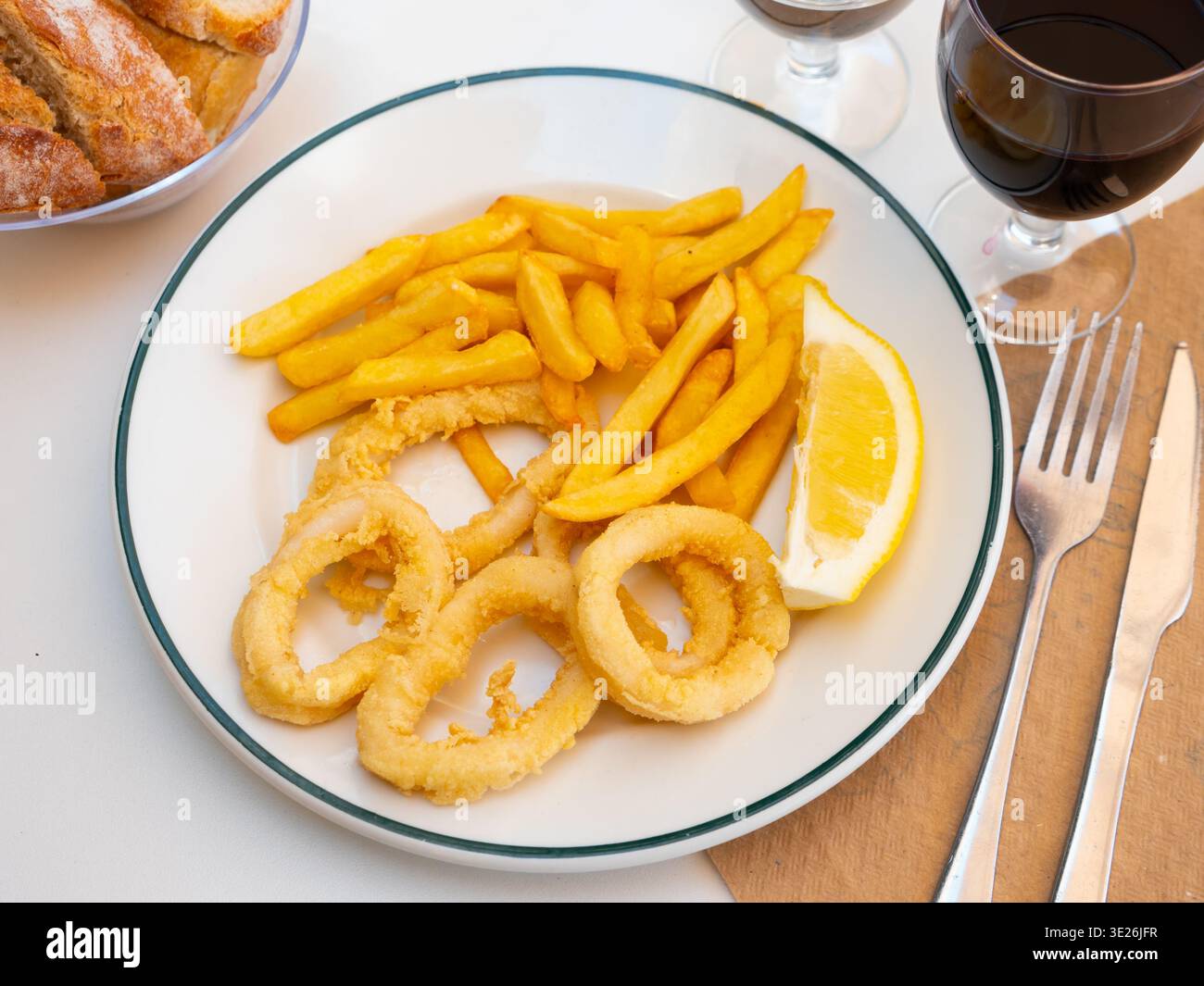 Frittierte Tintenfischringe mit Pommes frites und Zitrone Stockfoto