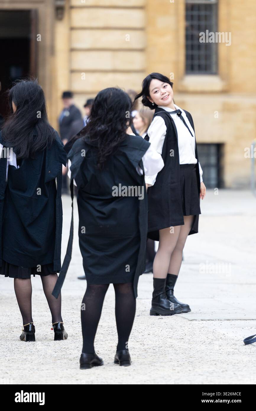 Glücklicher Student, der ein akademisches Kleid trägt, lächelt während einer Zeremonie auf dem Campus Stockfoto