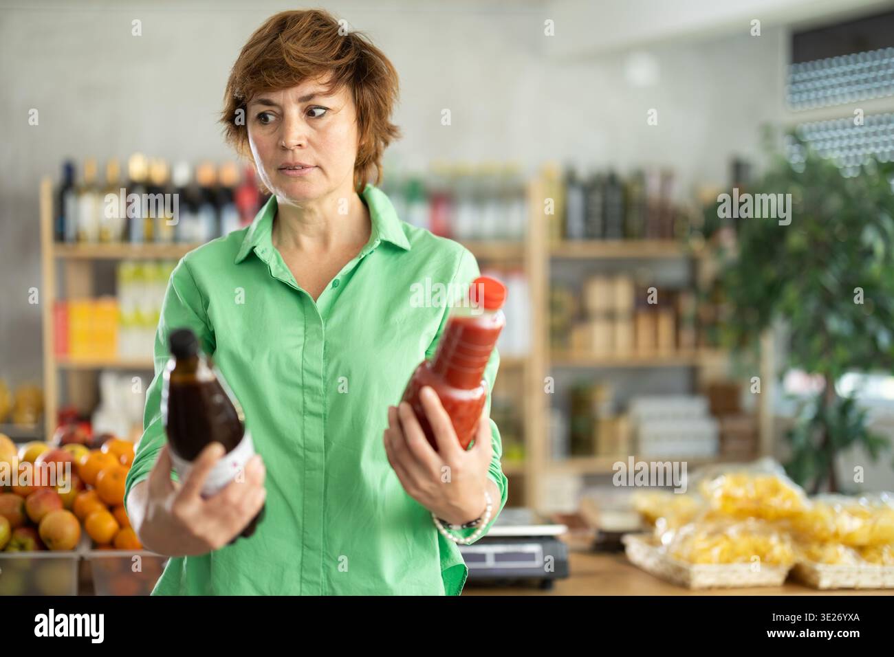 Erwachsene Frau, die Säfte wählt Stockfoto