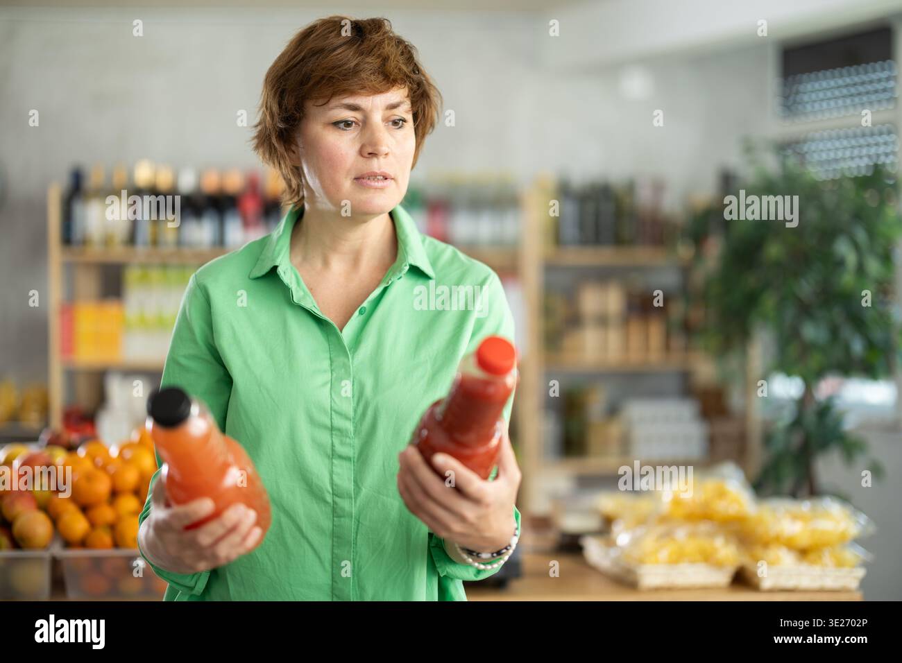 Erwachsene Frau, die Säfte wählt Stockfoto