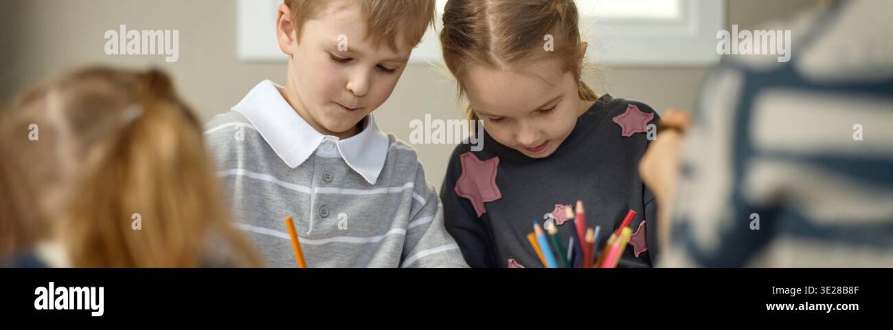 Kopfzeile der Kinder, die während der kreativen Aktivität im Kindergarten zusammen zeichnen Stockfoto
