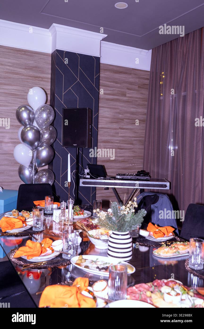 Elegantes Restaurant mit Tisch für ein formelles Dinner-Event mit Ballons in der Nähe. DJ-Kabine ist sichtbar. Konzept der luxuriösen Gastfreundschaft, festlicher Partyplaner Stockfoto