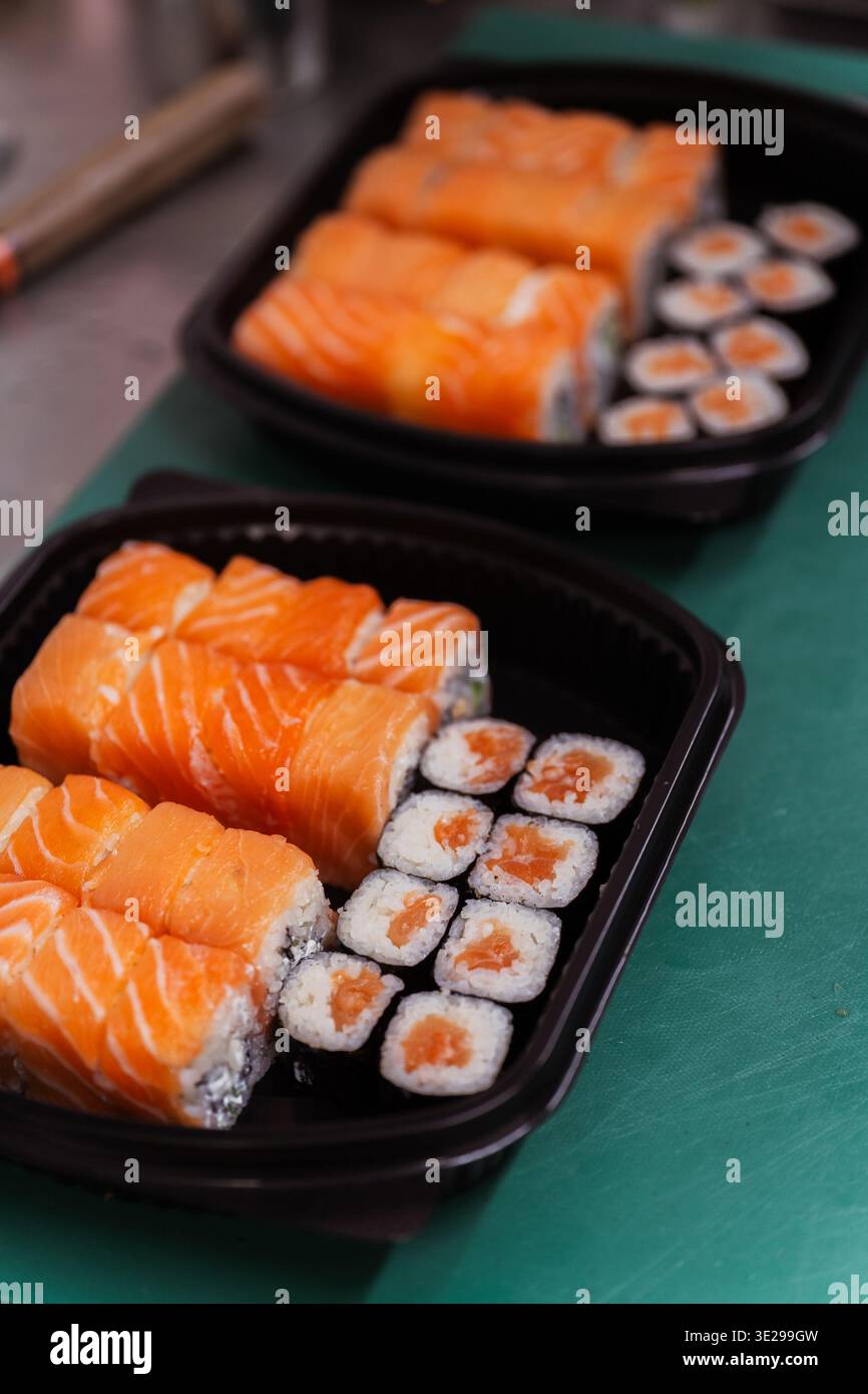 Readytoservieren Lachsushi Box Mit Rolls Und Maki, Ordentlich Angeordnet In Schwarzem Tablett, Kompaktes Mitnehmen Stockfoto