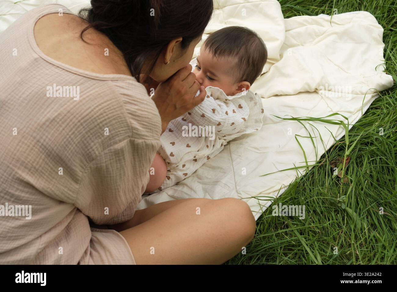 Gemütlichkeit und Sorgfalt prägen diese Szene, eine Mutter und ein Kind in einer ruhigen Kuschelei, umgeben von weichen Texturen. Zeigt den sanften Geist der Erziehung. Stockfoto