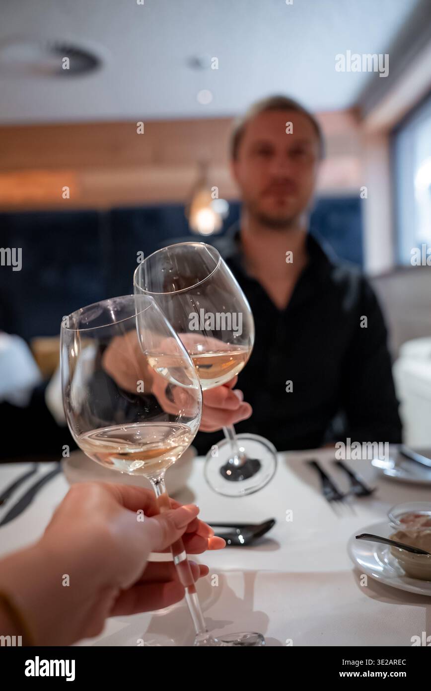 Weingläser klirren auf weißer Bettwäsche in einem Zermatter Boutique-Hotel Stockfoto