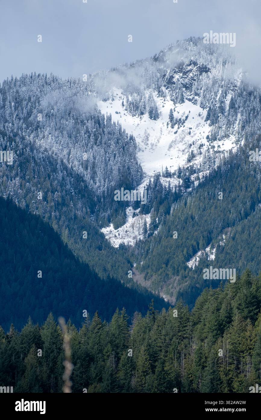 Vertikale Nahaufnahme des Berggipfels mit frischem Schnee vom Pitt Lake Dyke aus gesehen. Eine leichte Wolke hängt in der Nähe des Gipfels. Pitt Meadows, BC, Canad Stockfoto