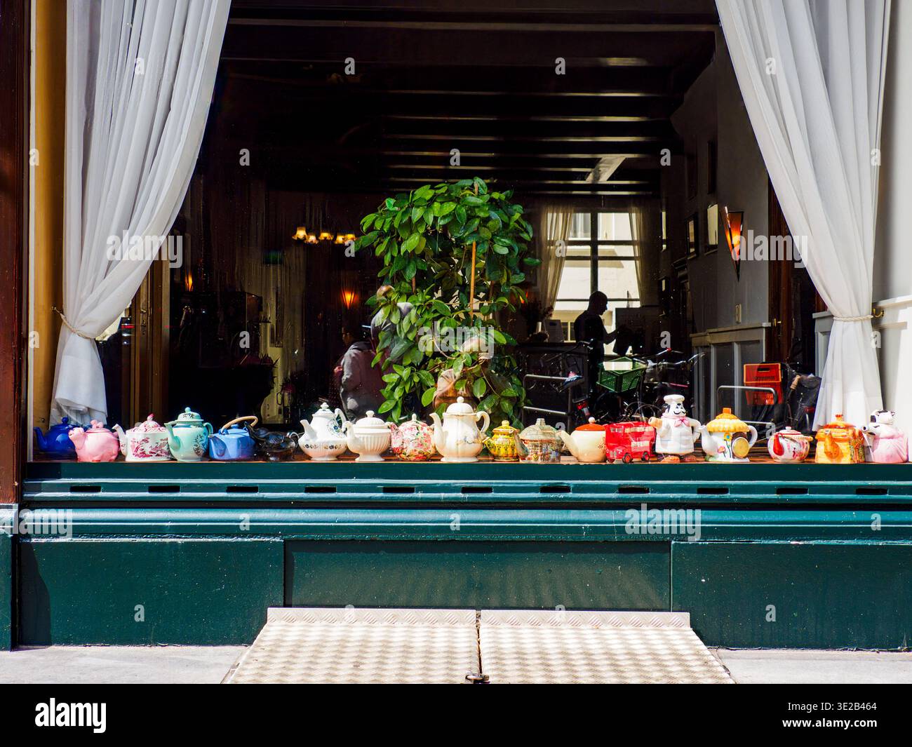 Ein gemütliches Schaufenster in Amsterdam, Holland, mit farbenfrohen Vintage-Teekannen und rustikalen Keramikküchen. Stockfoto