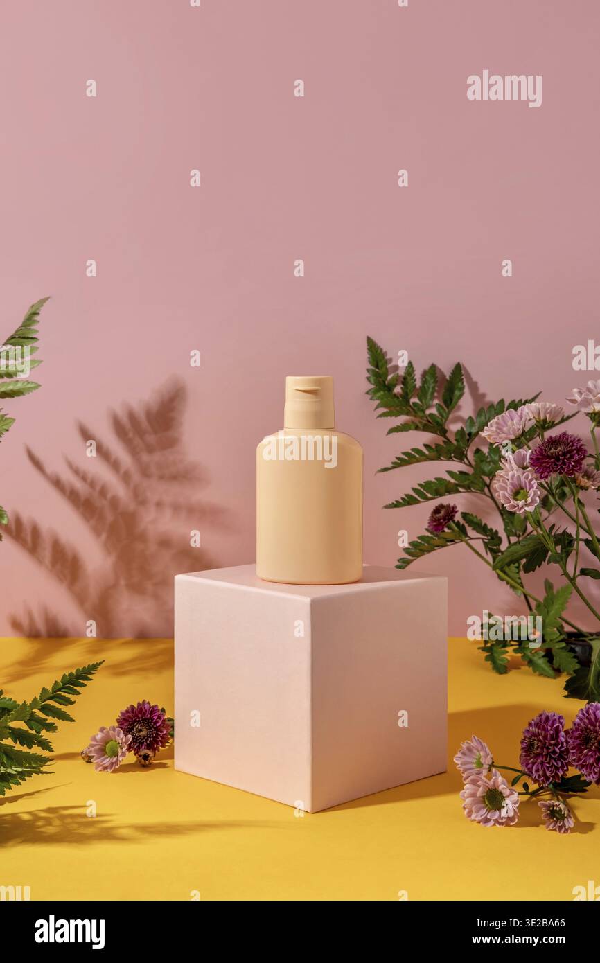Sommerstil der Schaufenster für Kosmetikprodukte auf gelbem und rosa Hintergrund. Flaschenkosmetik auf einem rosa Podium Stockfoto