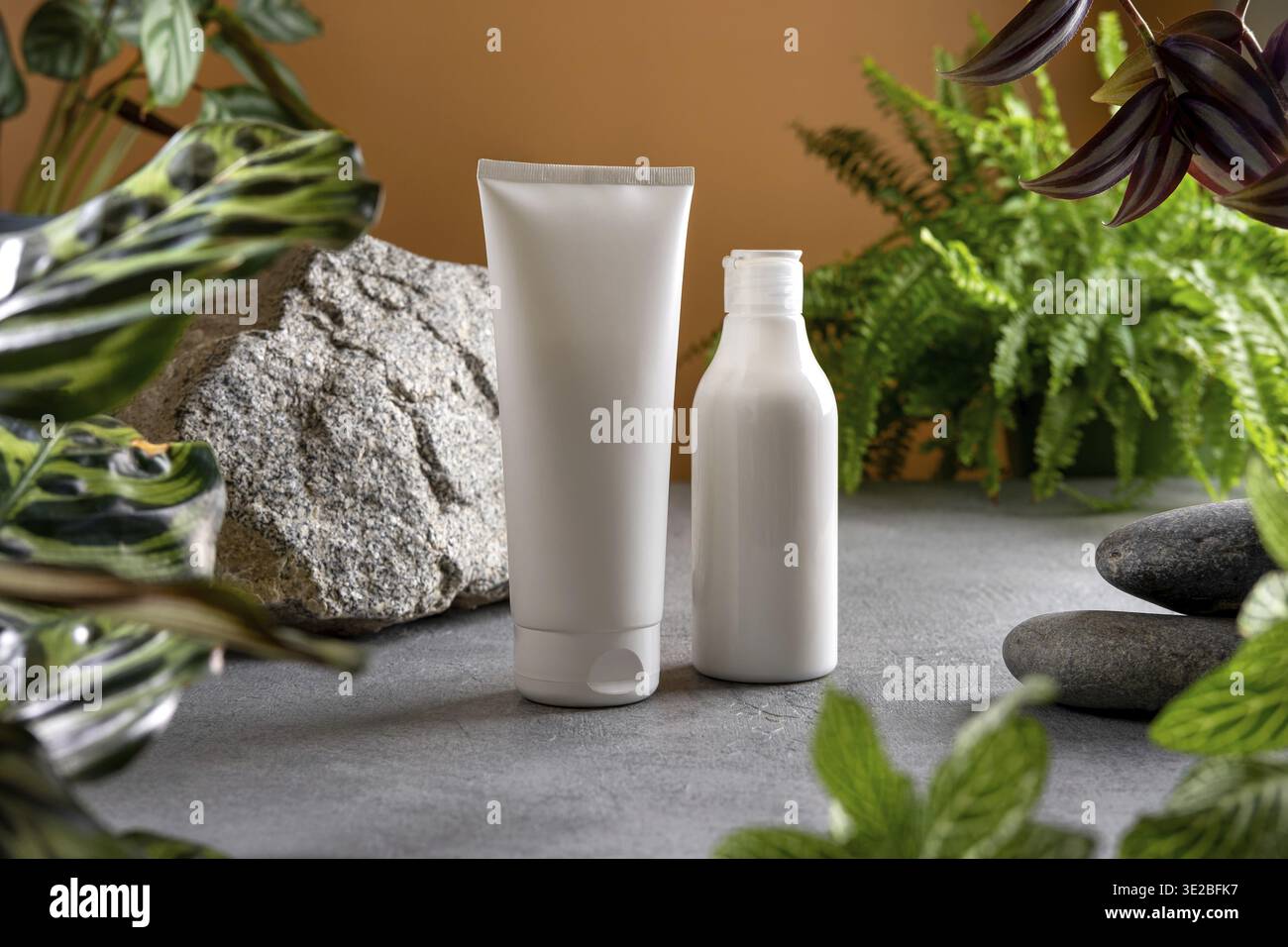 ?Osmetisches Produkt-Branding mit tropischen Blättern auf braunem Hintergrund. Werbung für Kosmetikprodukte mit natürlichen kosmetischen Inhaltsstoffen für Hautpflege und Körper Stockfoto