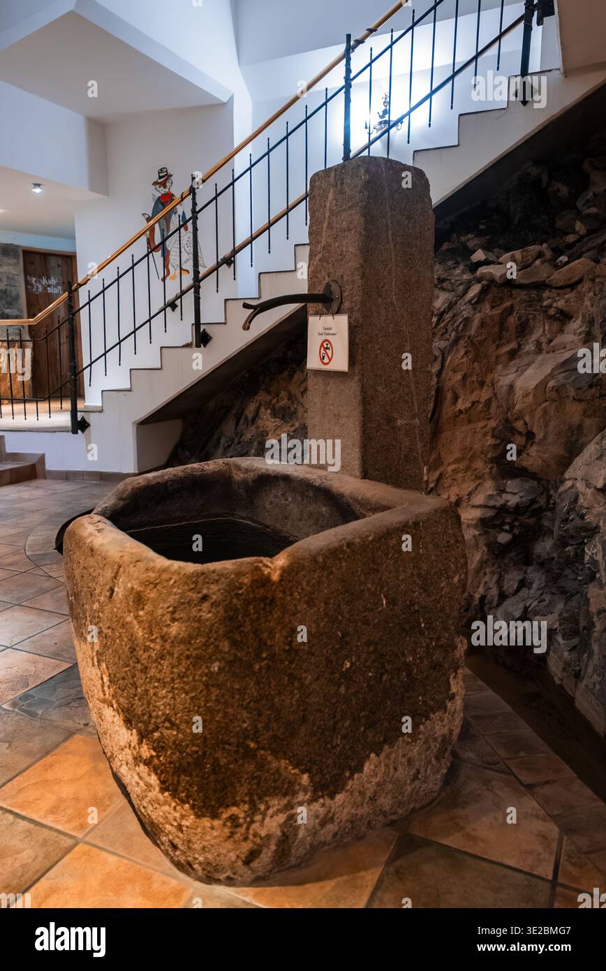 Rustikaler Steintrog und Säulenbrunnen im Innenbereich in Oberlech, Österreich Stockfoto