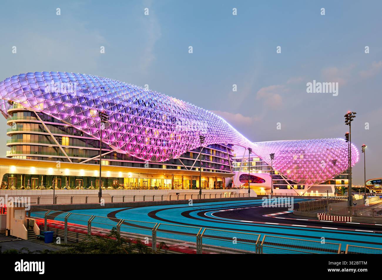 Das W Abu Dhabi Hotel hebt sich auf Yas Island mit hellen Lichtern ab, wenn sich die Nacht nähert. Besucher genießen das moderne Design und die Umgebung. Stockfoto