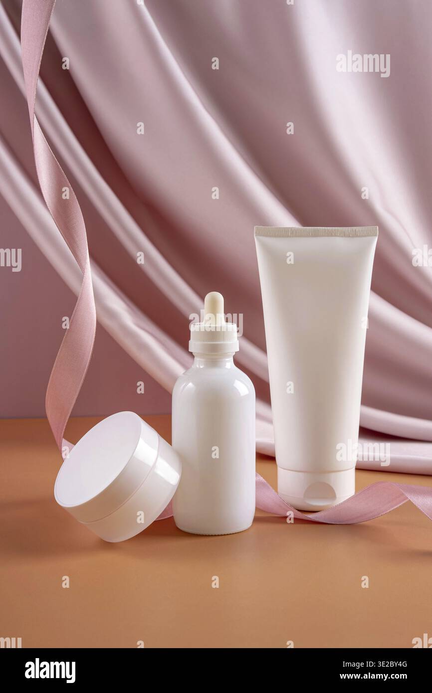 Drei weiße Flaschen kosmetisches Produkt auf pastellfarbenem Textil Hintergrund. Produktkonzept für Kosmetik Stockfoto