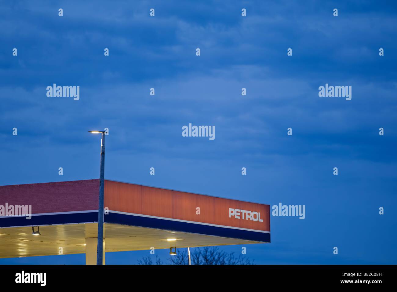 Vinkovci, Kroatien - 19. Februar 2026: Leerer Tankstellenvorhang, beleuchtet in der Abenddämmerung vor einem stimmungsvollen blauen Himmel, mit einer beleuchteten Straßenlaterne und sichtbar Stockfoto