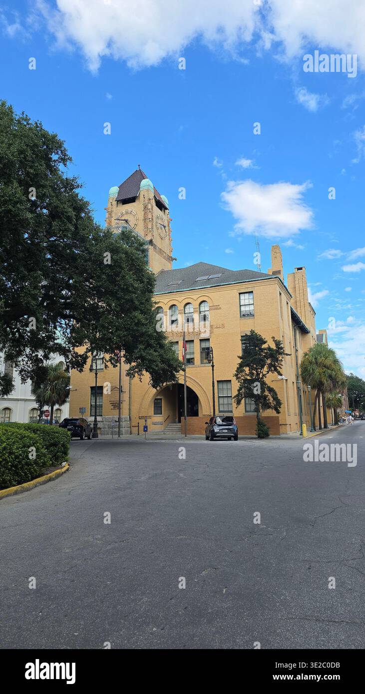 Historisches beigefarbenes Backsteingebäude mit Uhrenturm im Zentrum von Savannah, Georgia, USA, unter blauem Himmel mit Wolken - Smartphone-aufgenommenes Stockfoto