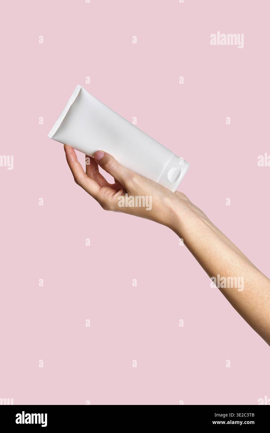 Frau Hand zeigt Creme Produkt. Mockup für das Branding von Kosmetikprodukten. Tägliche Hautpflege und Körperpflegeroutine. Weibliche Hand, die kosmetisches Produkt-Modell hält Stockfoto