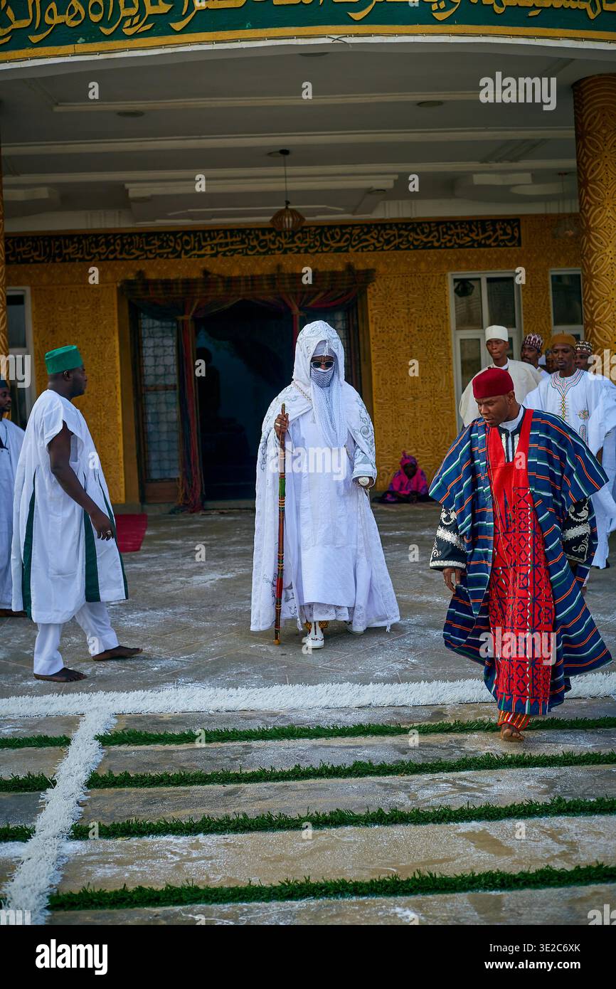 Kano, Nigeria - 17. März 2022: Blick auf eine zentrale Figur in weißen Gewändern, die die Stufen hinabsteigt, flankiert von Zuschauern in farbenfroher traditioneller Kleidung, Agai Stockfoto