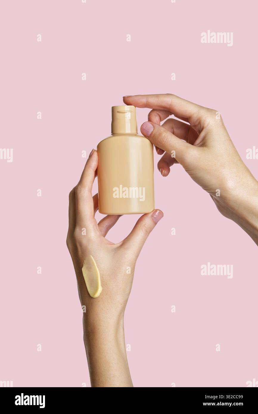 Frau Hand zeigt Creme Produkt. Mockup für das Branding von Kosmetikprodukten. Tägliche Hautpflege und Körperpflegeroutine. Weibliche Hand, die kosmetisches Produkt-Modell hält Stockfoto
