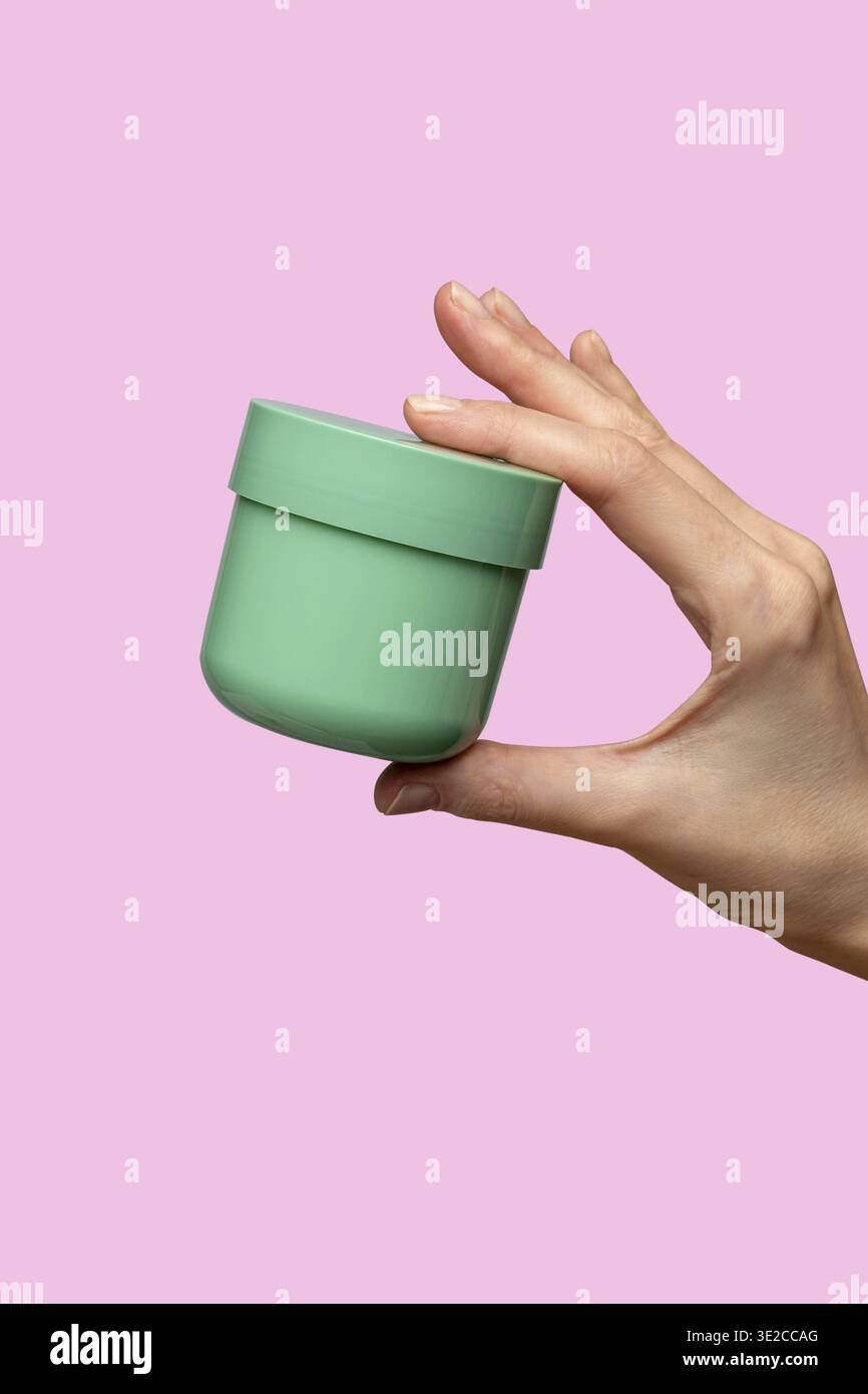 Frau Hand zeigt Creme Produkt. Mockup für das Branding von Kosmetikprodukten. Tägliche Hautpflege und Körperpflegeroutine. Weibliche Hand, die kosmetisches Produkt-Modell hält Stockfoto