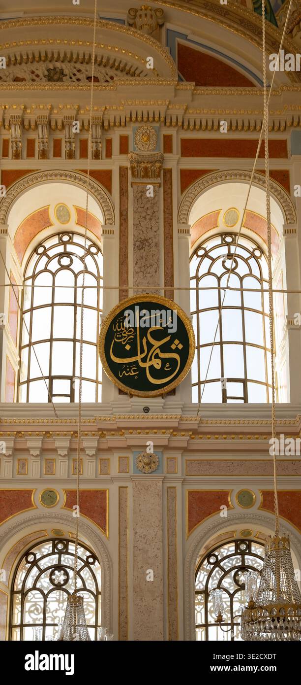Dekorative Innenausstattung mit hohen Bogenfenstern, arabischem Kalligraphiemedaillon und komplizierten Goldverzierungen. Elegante religiöse Architektur Stockfoto