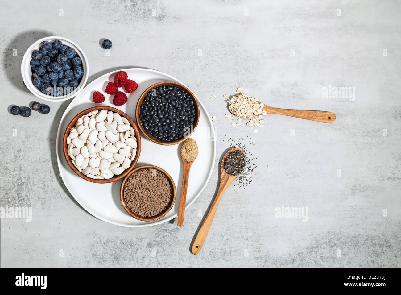 Flaches Lagen von Supernahrungsmitteln mit hohem Ballaststoffanteil, einschließlich Bohnen, Linsen, Hafer und Beeren für den Fasermaxing-Nährstofftrend Stockfoto